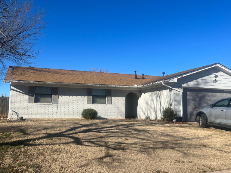 Completed brown asphalt shingle roof on brick home in Lawton Oklahoma under blue sky