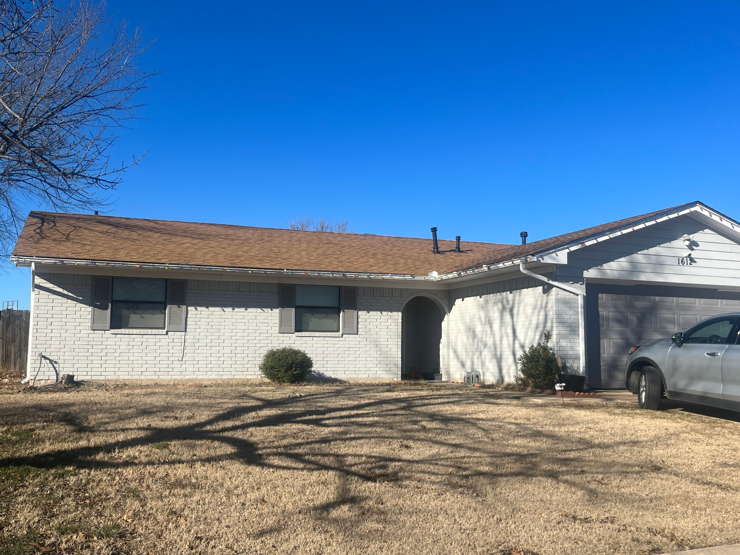 Completed brown asphalt shingle roof on brick home in Lawton Oklahoma
